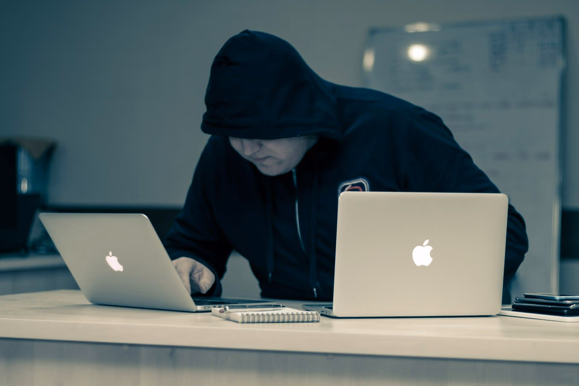 A hacker working on two laptops (Azamat E/Unsplash)